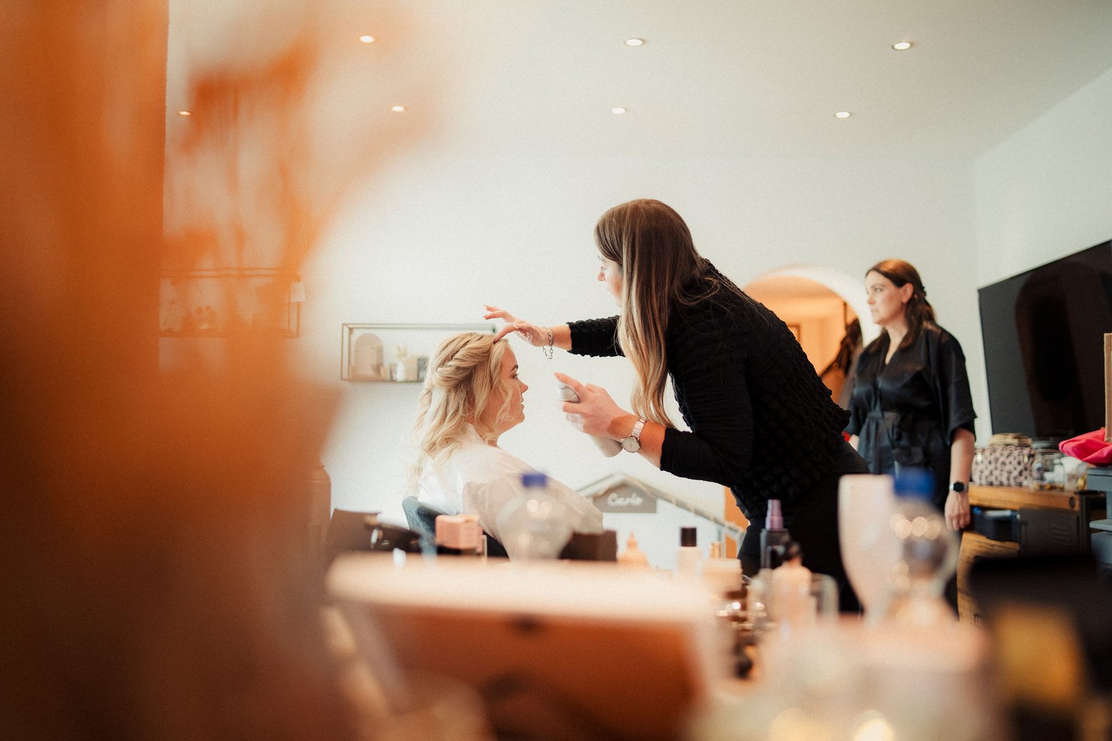 Braut beim Make-up, fotografiert durch den Raum